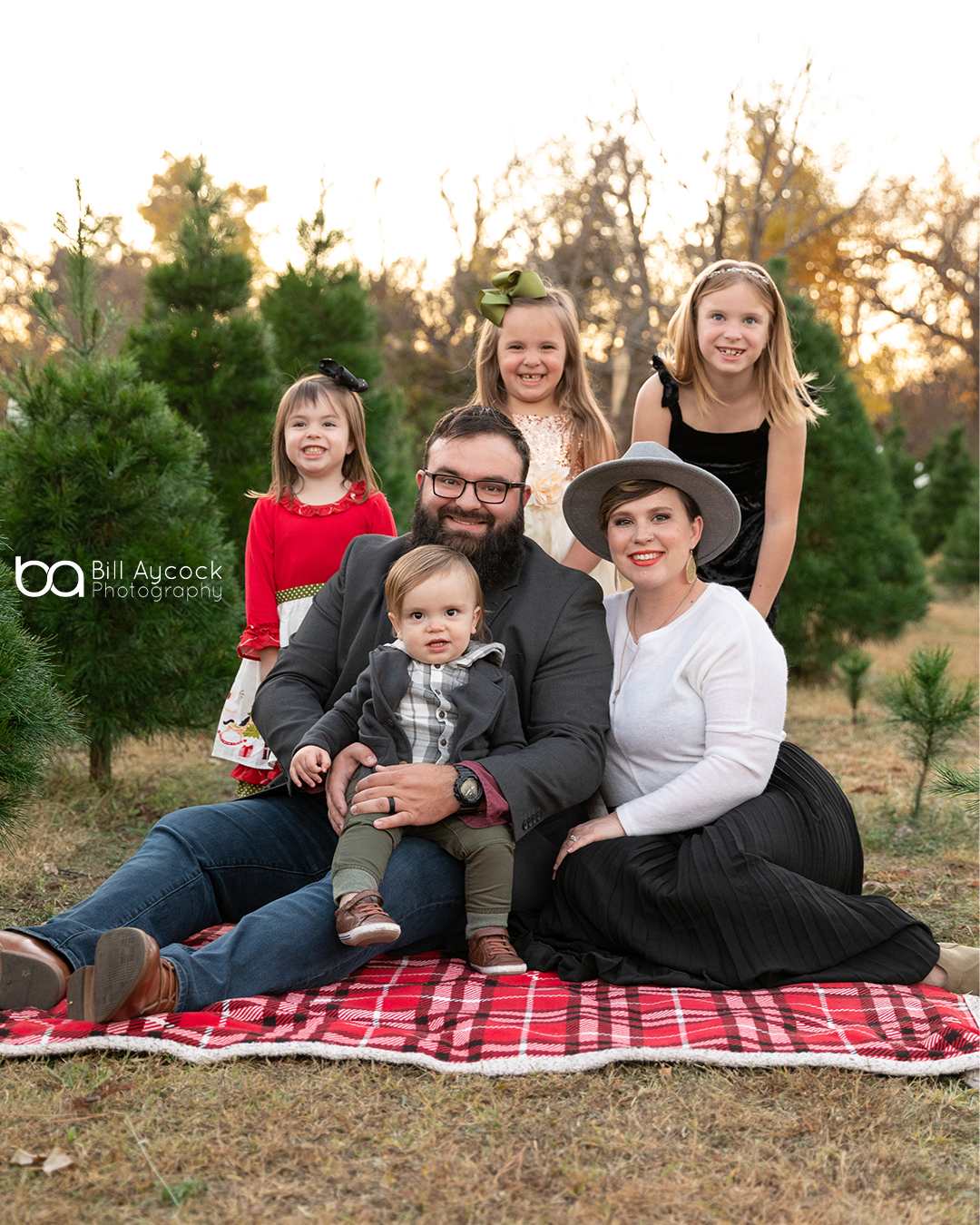 OKC Family posing for Christmas Photos In a Tree Farm
