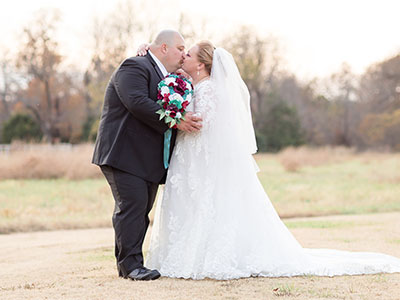 Bride and Groom embracing and kissing in open field